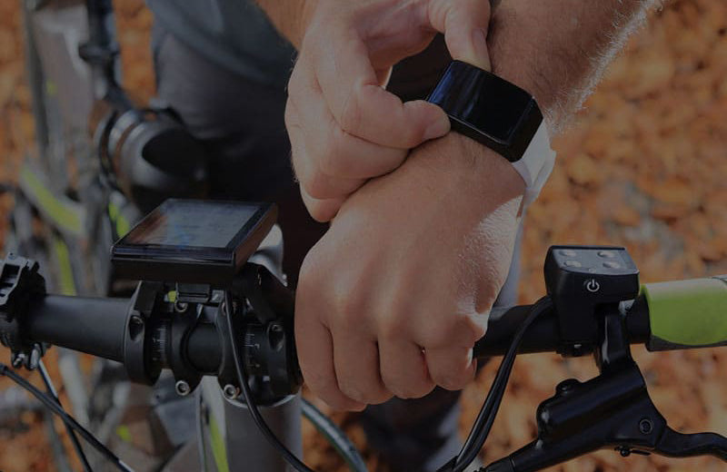An individual fixing their smart watch with their bicycle accompanied in the photograph